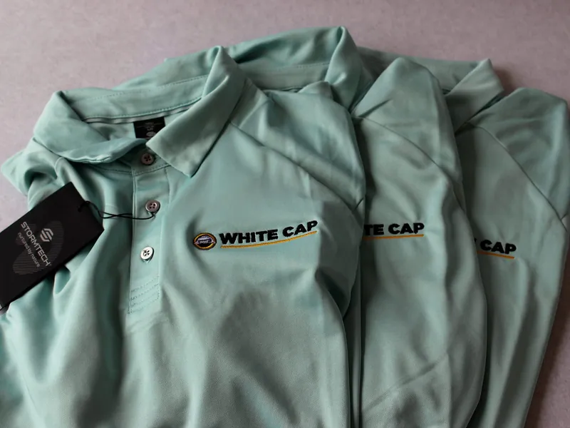 Stack of finished branded polos, folded, logo visible