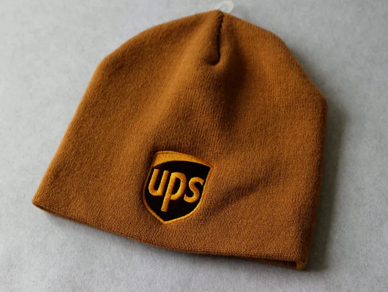 Brown knit beanie with a shield logo