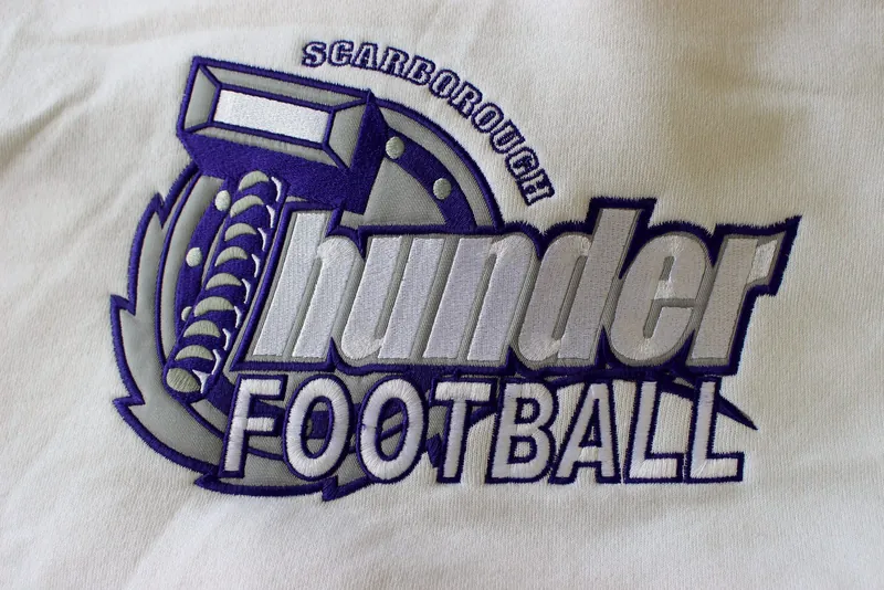 Purple and grey football club logo on white fleece
